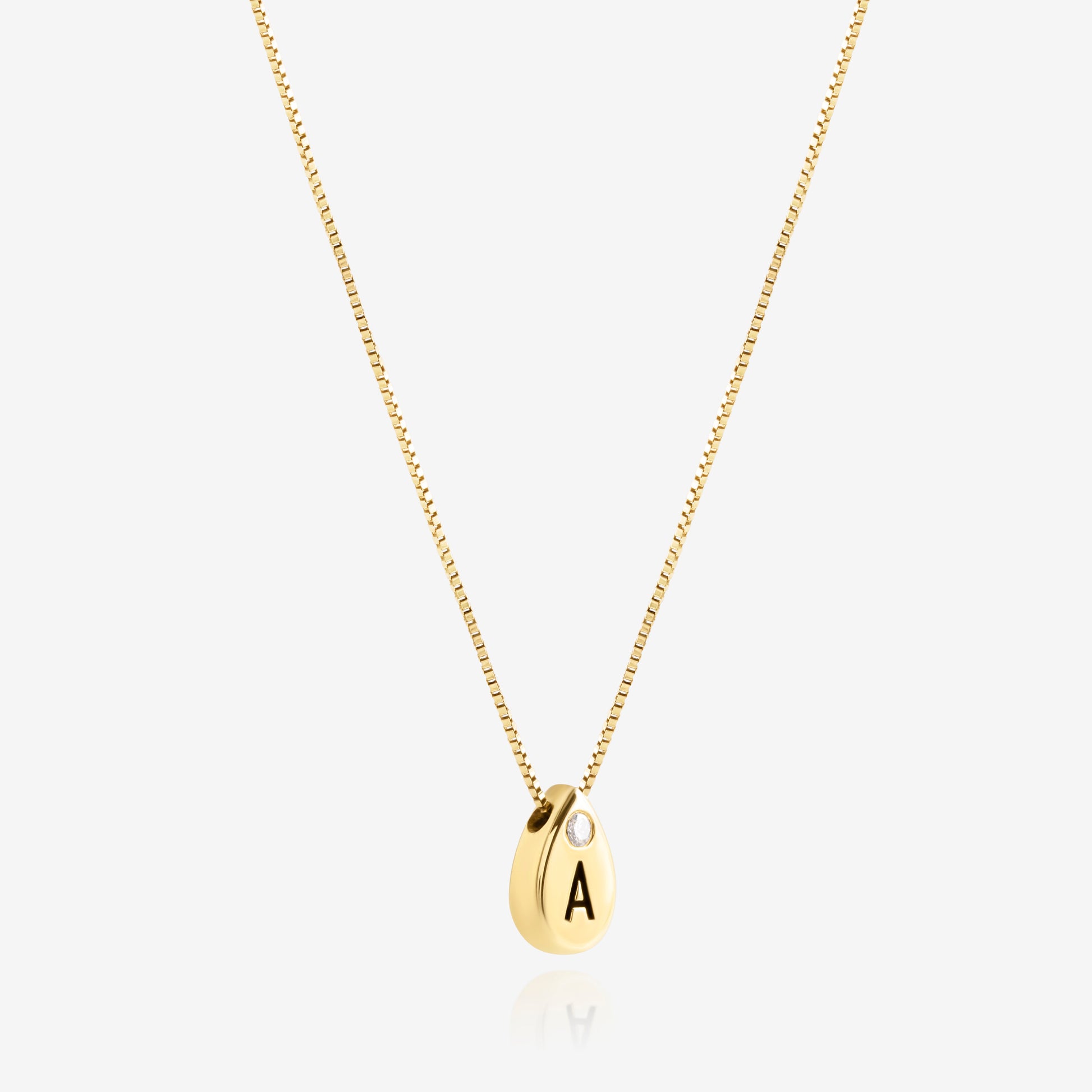 Side view of personalized 14K gold teardrop initial necklace showing engraved letter and diamond detail.